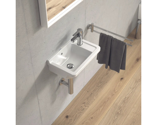 Moderní koupelna s malým umyvadlem, baterií, držákem na ručníky a zrcadlem