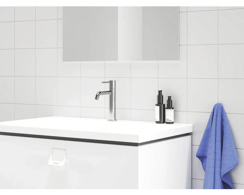 Moderní koupelnové umyvadlo s baterií, ručníkem a kosmetikou