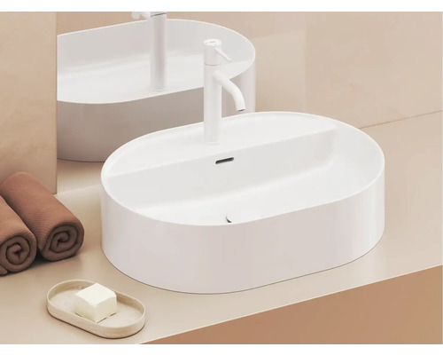 Na umyvadle je oválné umyvadlo na desku, vodovodní baterie, ručníky a mýdlo.