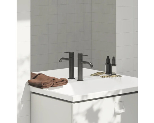 Koupelna s umyvadlovou skříňkou, bateriemi, ručníkem a kosmetickými produkty