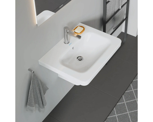 Bílé umyvadlo na desku s vodovodní baterií, mýdlenkou a držákem na ručníky v koupelně.