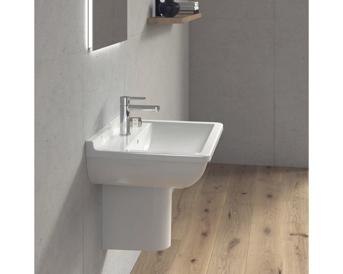 Moderní koupelna s bílým umyvadlem a baterií na betonové zdi.