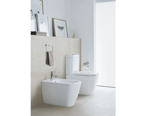 Moderní koupelna s bidetem a toaletou v bílé barvě, navíc držák na ručníky a dekorace