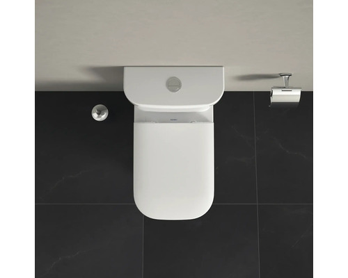 Pohled shora na bílou stojící toaletu s nádržkou, držákem toaletního papíru a splachovacím tlačítkem