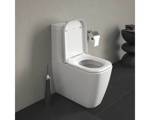 Bílá stojící toaleta s otevřeným záchodovým prkénkem a držákem toaletního papíru v koupelně