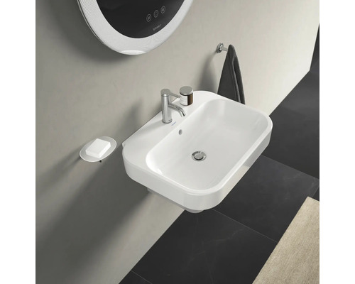 Světlá koupelna s umyvadlem, dávkovačem mýdla, zrcadlem a držákem na ručníky.