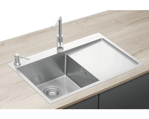 Nerezový dřez s odkapávací plochou, vodovodní baterií a dávkovačem mýdla na pracovní desce.