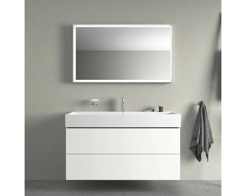 Moderní koupelna s umyvadlovou skříňkou, umyvadlem, osvětleným zrcadlem, mýdlenkou a držákem na ručníky.