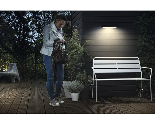 Žena stojí na terase pod venkovní lampou
