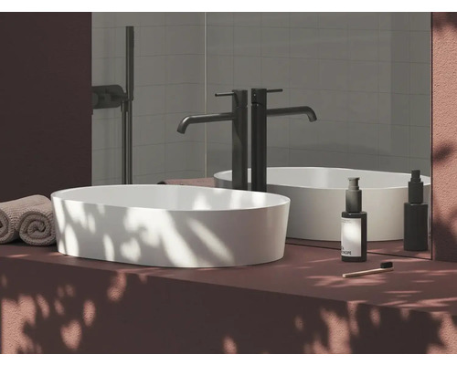 Moderní umyvadlo v koupelně s baterií, ručníky a pečujícími produkty