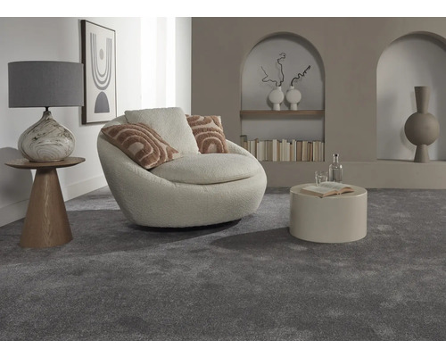 Interiérová fotografie obývacího pokoje s šedým kobercem, křeslem, stolem a dekorativními prvky