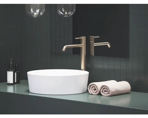 Koupelna s umyvadlem na desku, baterií, ručníky a kosmetickými produkty