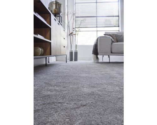 Interiérová fotografie obývacího pokoje se šedým kobercem, příborníkem, pohovkou a oknem se žaluziemi