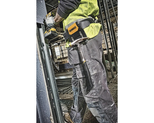 Stavební dělník s opaskem na nářadí, kladivem a akumulátorovým šroubovákem na staveništi