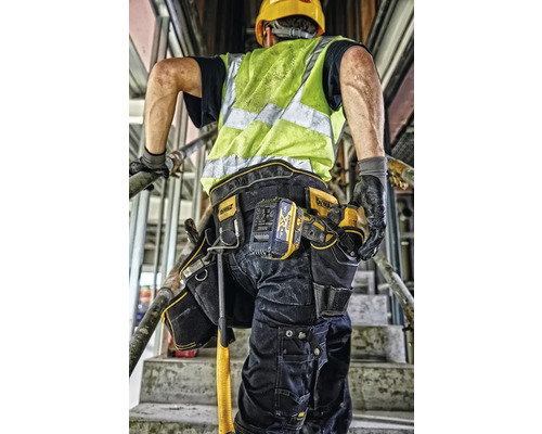 Stavební dělník s opaskem na nářadí a bezpečnostní vestou na staveništi