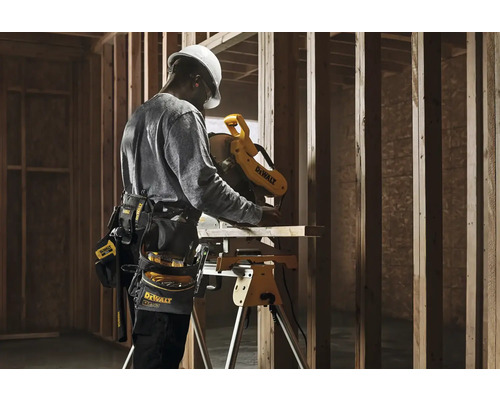 Řemeslník pracuje s pokosovou pilou DeWalt na staveništi