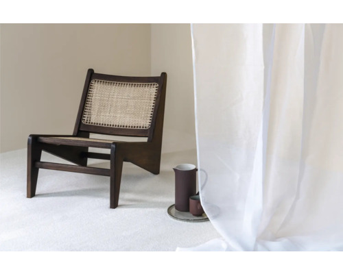 Scéna s tmavou dřevěnou židlí s ratanovým sedákem, džbánem a šálkem na podnosu a průhledným závěsem.