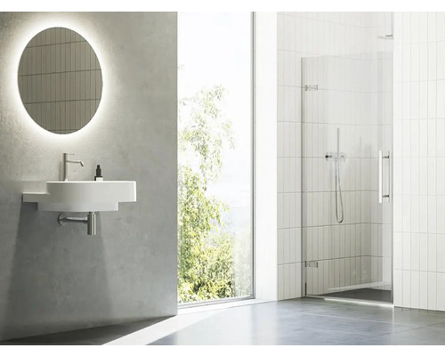 Světlá koupelna s umyvadlem, zrcadlem a sprchovým koutem.