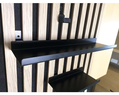 Černá kovová police na dřevěné lamelové stěně