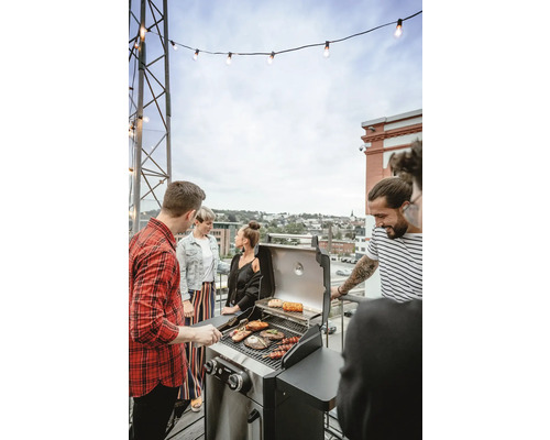 Skupina lidí griluje venku na plynovém grilu