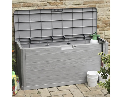 Otevřený šedý zahradní box z plastu s vzhledem dřeva před cihlovou zdí