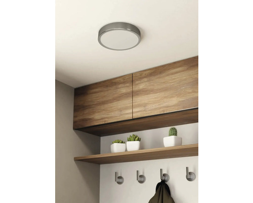 Stropní svítidlo v jasném pokoji s dřevěnými skříněmi, policí a věšákem.