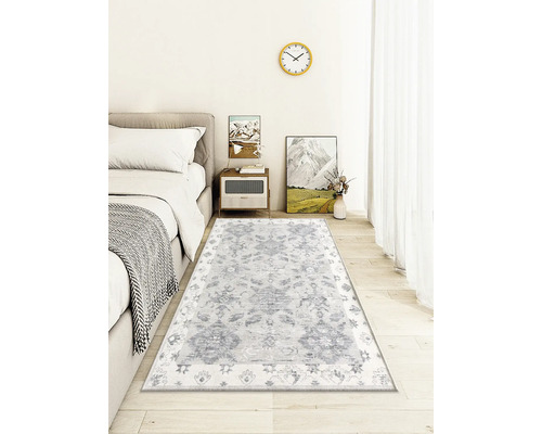 Dekorativní obývací pokoj se vzorovaným kobercem pod postelí.