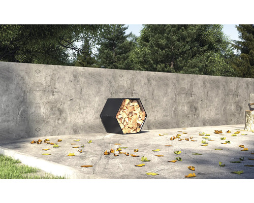 Šestiúhelníkový kovový koš na dřevo plný dřeva venku před betonovou zdí