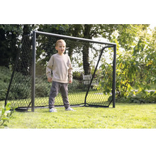 Chlapec stojí před fotbalovou brankou na zahradě.