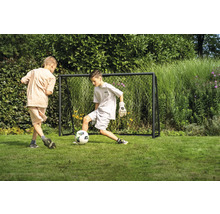 Dva chlapci hrají fotbal před fotbalovou brankou na zahradě.