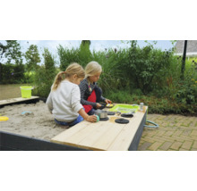 Dvě děti si hrají na pískovišti s hrací kuchyní na zahradě.