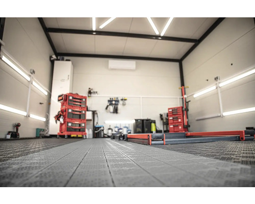 Světlá dílna s vozíky na nářadí, ponkem a podlahovými ochrannými rohožemi