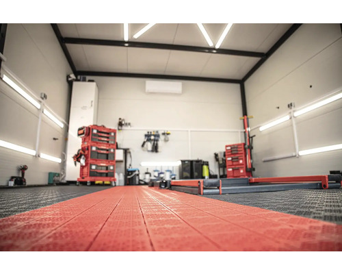 Dílna s vozíky na nářadí, vybavením a podlahovými krytinami.