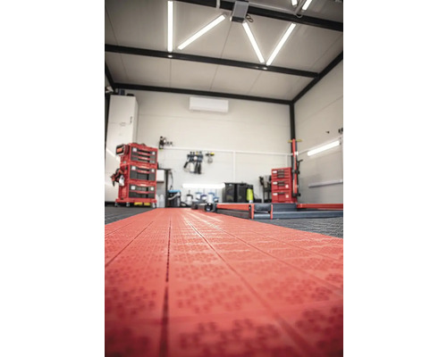 Dílna s červenou podlahovou krytinou, vozíkem na nářadí a pracovním stolem