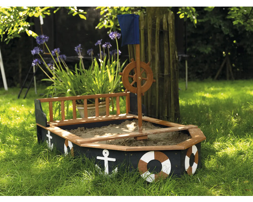 Pískoviště ve tvaru lodi s kormidelním kolem, vlajkou a námořními dekoracemi na zahradě