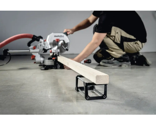 Pokosová pila Metabo řeže kus dřeva s opěrkou obrobku.