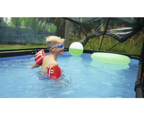 Dítě s plovacími rukávky a plaveckými brýlemi v bazénu pod bazénovou kupolí