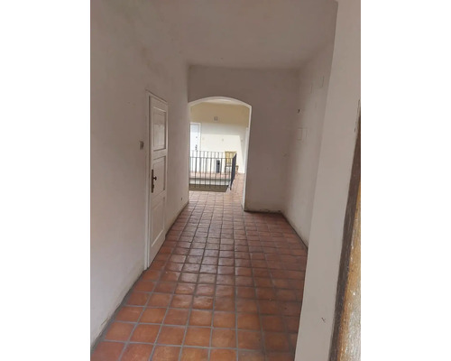 Chodba s terakotovými dlaždicemi, bílými dveřmi a obloukem