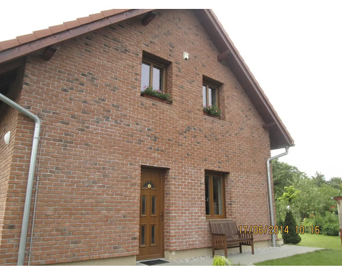 Pohled na dům s cihlovým zdivem, okny a dřevěnými dveřmi