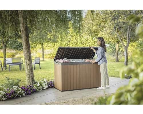 Zahradní scéna s ženou, která se dívá na otevřený úložný box na zahradě