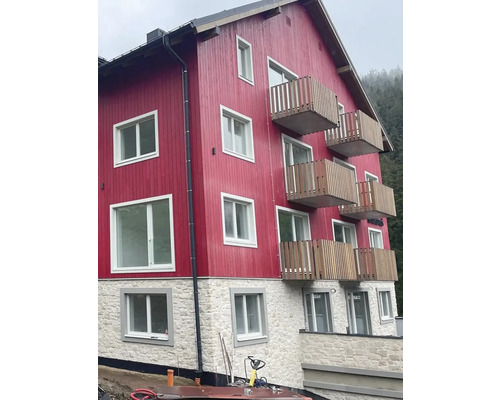 Vícepatrová budova s dřevěnou fasádou, balkony a kamennými základy