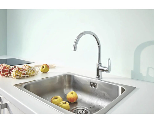 Kuchyňská baterie s jablky a síťovanou taškou ve světlé kuchyni.