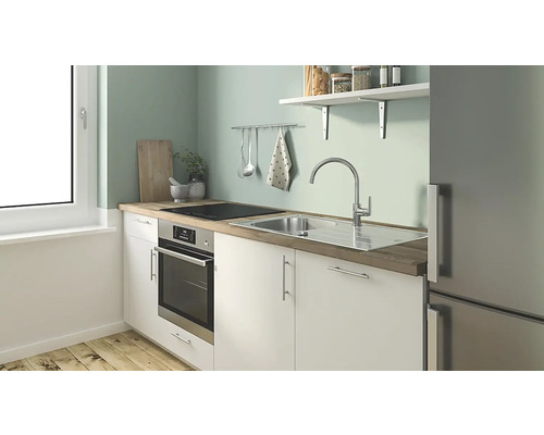 Kompaktní kuchyně s umyvadlem, varnou deskou a troubou ve světlé místnosti