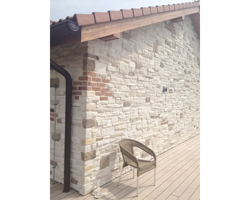 Vnější stěna s obkladovými kameny, střecha s taškami a židle na terase