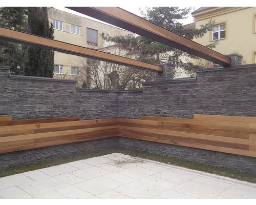 Venkovní prostor s kamennou zdí, dřevěnými lavicemi a pergolou