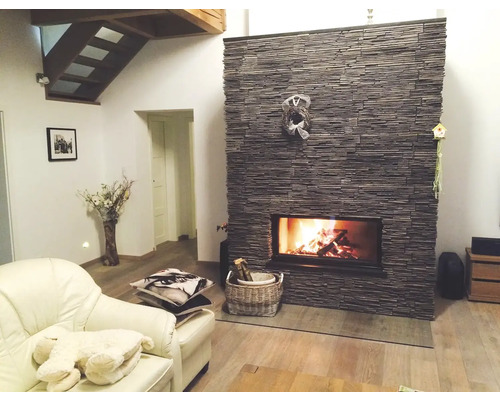 Obývací pokoj s kamenným krbem, křeslem a dřevěným schodištěm