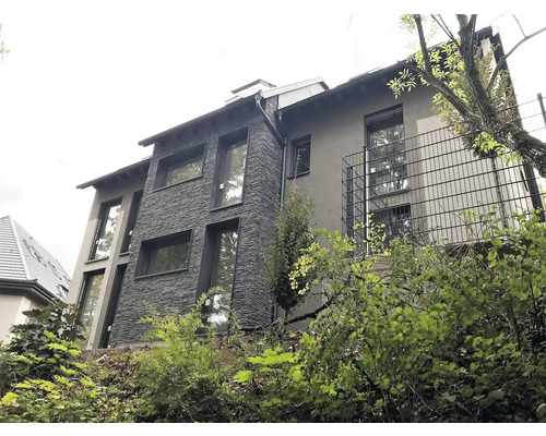 Vícepodlažní obytný dům s fasádou z kamene a omítky a několika okny.