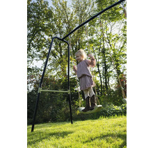 Dívka se houpe na houpačce na zahradě.