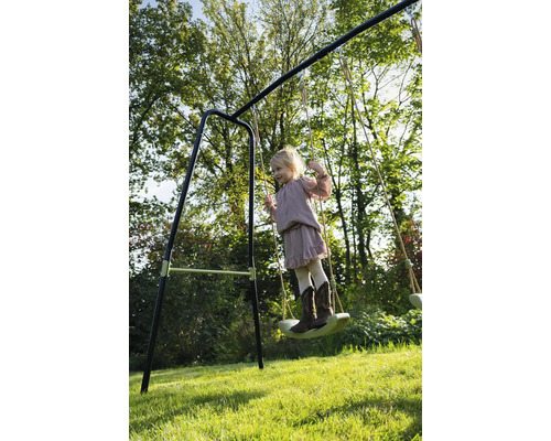 Dívka se houpe na houpačce na zahradě.