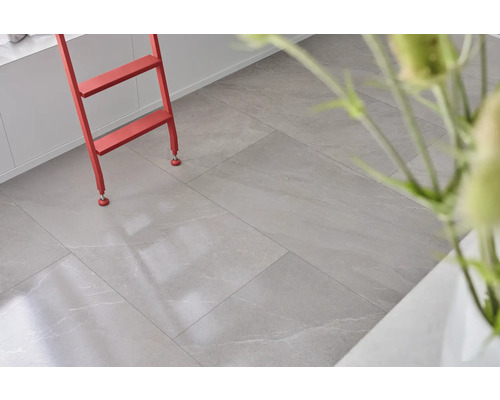 Světlá místnost s podlahovými dlaždicemi se vzhledem kamene a červeným žebříkem